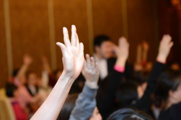 Students putting hands up in lecture theatre Students putting hands up in lecture theatre