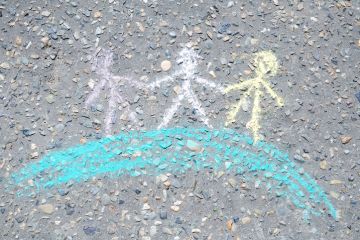 Chalk figures holding hands on a globe