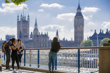 London, UK - September 10, 2015 Tourists talking and making a photos against of Houses of Parliament. View from the Thames embankment. London