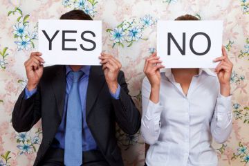 Man and woman holding yes/no cards in front of faces Man and woman holding yes/no cards in front of faces