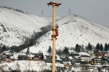 Man climbing wooden column, Krasnoyarsk, Siberia Man climbing wooden column, Krasnoyarsk, Siberia