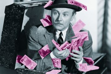 Man crouching in box full of cash Man crouching in box full of cash