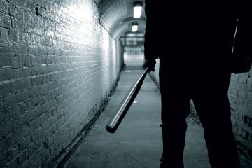 Man holding baseball bat in tunnel Man holding baseball bat in tunnel