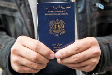 Man holds Syrian passport, Luebeck, Germany, 2015 Man holds Syrian passport, Luebeck, Germany, 2015
