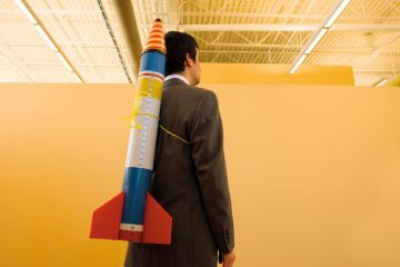 Man in suit with rocket strapped to back Man in suit with rocket strapped to back