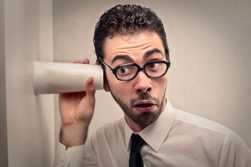 Man listening through wall with cup