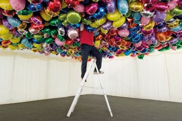 Man on ladder with head in balloons Man on ladder with head in balloons