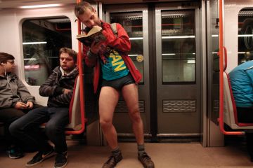 Man reading book on subway train, No Pants Subway Ride, Prague, 2015 Man reading book on subway train, No Pants Subway Ride, Prague, 2015