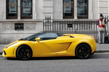 Man selling Big Issue next to Lamborghini, Covent Garden, London Man selling Big Issue next to Lamborghini, Covent Garden, London