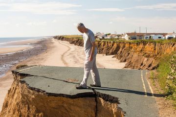Man standing on the edge of an eroded cliff Man standing on the edge of an eroded cliff