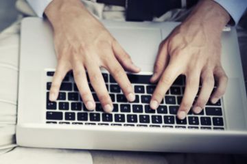 Man typing on Apple MacBook laptop keyboard Man typing on Apple MacBook laptop keyboard