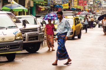 Man walking across congested street, Yangon, Myanmar Man walking across congested street, Yangon, Myanmar