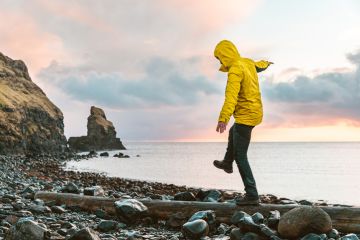 Man hanging in the balance over a log at seaside in Scotland