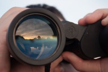 Man looking through binoculars illustrating op-ed by Stephen Toope about University of Cambridge principles around international engagement