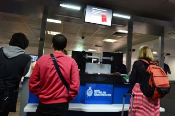 Melbourne, Australia - April 10, 2014 Passengers stand at an Australian Customs and Border Protection checkpoint in Melbourne airport. The agency responsible for the safety, security and commercial interests of Australians
