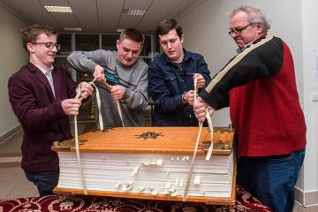 Men struggling to lift a giant book. To illustrate that three major research universities have opted out of new Elsevier deal amid concerns over the cost. Men struggling to lift a giant book. To illustrate that three major research universities have opted out of new Elsevier deal amid concerns over the cost.
