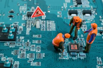 Figures of humans stand and squat on a motherboard