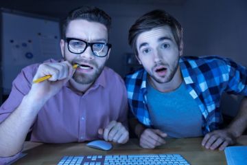 Men peering confused into computer screen