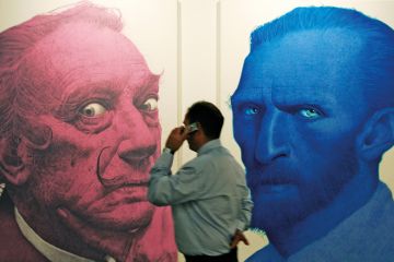 A man phones in front of portraits of the Salvador Dali (L) and Vincent Van Gogh (R) A man phones in front of portraits of the Salvador Dali (L) and Vincent Van Gogh (R)