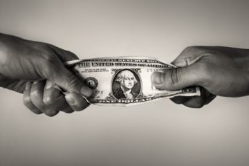 People pull on a dollar bill, illustrating competition for resources