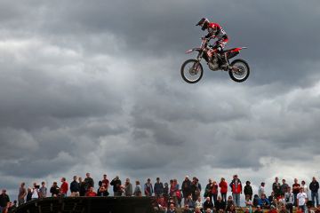 Person on a motorbike jumping above crowd of spectators. To illustrate wages rising faster at universities outside national bargaining.