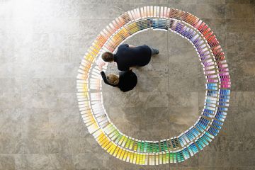 People examining circle of paint swatches, viewed from above People examining circle of paint swatches, viewed from above