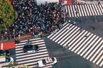 Crowd of people waiting to cross at Shibuya pedestrian crossing, Tokyo, Japan. To illustrate Asian students deciding on where to study, and whether they will switch to cheaper, safer and friendlier options closer to home.