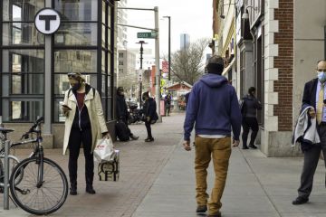 People pass each other on a non crowded street in Cambridge, MA during COVID-19 wearing face mask.