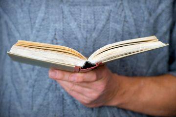 Person holding open book in hand Person holding open book in hand