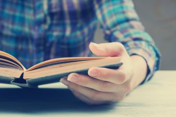 Person sat reading book at table Person sat reading book at table