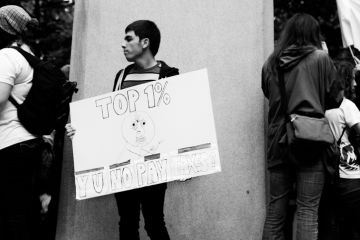 Portland, Oregon, USA - October 6, 2011 A young man holds a sign that reads Top 1٪ Y U No Pay Taxes during an Occupy Wall Street event in downtown Portland. Portland, Oregon, USA - October 6, 2011 A young man holds a sign that reads Top 1٪ Y U No Pay Taxes during an Occupy Wall Street event in downtown Portland.