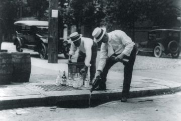Men pouring alcohol down drain during prohibition Men pouring alcohol down drain during prohibition