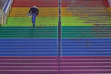 Person running up rainbow stairs to illustrate LGBTQ exam performance