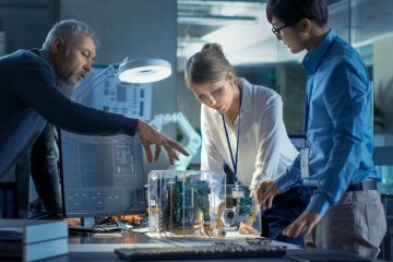 Scientists and business people discuss a computer component