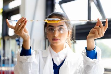 An Asian student holds a pipette level, symbolising equlaity in international collaboration 