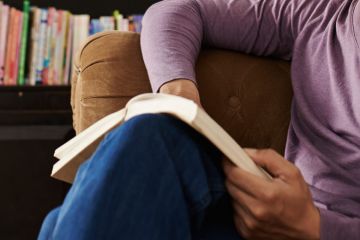 Seated man on sofa reading book Seated man on sofa reading book