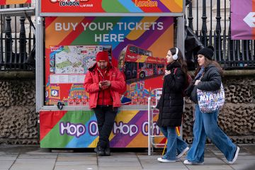Official City Sightseeing tour bus ticket booth with tourists walking past on 19th February 2025 in London, UK. To illustrate that the Policy Exchange thinktank suggests charging a levy to foreign students, not universities.