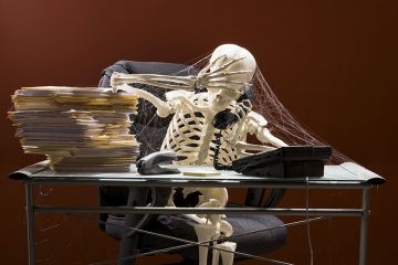 Skeleton sitting at desk on telephone, with webs and stacks of paperwork. To illustrate that colleges are in limbo amid ‘two-year wait’ for degree-awarding powers. Skeleton sitting at desk on telephone, with webs and stacks of paperwork. To illustrate that colleges are in limbo amid ‘two-year wait’ for degree-awarding powers.