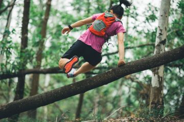 Sportswoman cross country trail running in forest