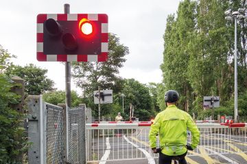 A cyclist stops at a red light at a level crossing A cyclist stops at a red light at a level crossing to illustrate PhD enrolment hangs on an email