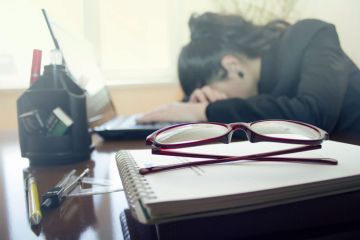 Stressed woman with head on desk Stressed woman with head on desk