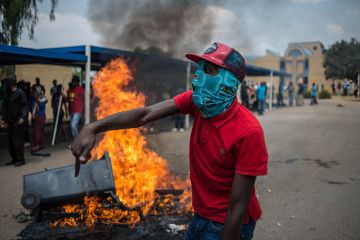 Students shout slogans next to a burning barricade during clashes with South African anti-riot police and campus security at a demonstration in support of the Fees Must Fall movement in 2016