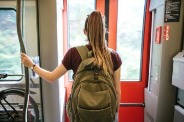 student with a backpack waiting for the train to stop to go outside