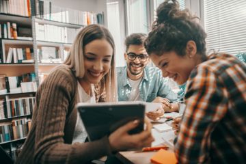 A group of students look at a tablet