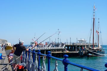 Swanage, United Kingdom - July 19, 2016 Tourists of the Victorian pier enjoying the Summer sunshine