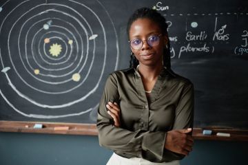 A black physics teacher stands in front of the blackboard A black physics teacher stands in front of the blackboard