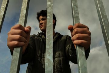 Teenage boy hands holding strong iron bar