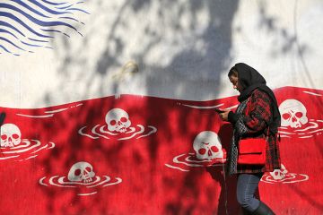 A woman walks past an anti-American murals following a possible US intervention against Iran on 28 January, 2026 in Tehran, Iran. A woman walks past an anti-American murals following a possible US intervention against Iran on 28 January, 2026 in Tehran, Iran.
