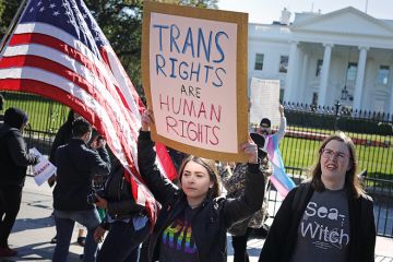 Woman holding up sign saying ‘trans rights are human rights’ at rally