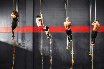 Crossfitters climbing up ropes